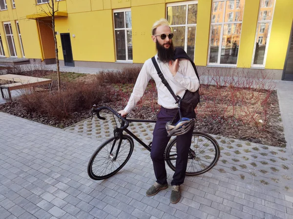 Młody, stylowy hipster pozujący obok roweru. — Zdjęcie stockowe