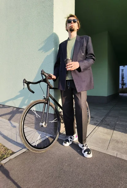 Millennial con una bicicleta beber café al aire libre — Foto de Stock