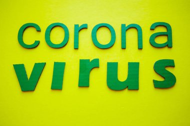 Kelime CORONAVIRUS yeşil karton harflerden yapılmış, sarı arka planda izole. Dünya Sağlık Örgütü WHO, COVID-19 adlı Coronavirus hastalığına yeni bir resmi isim verdi