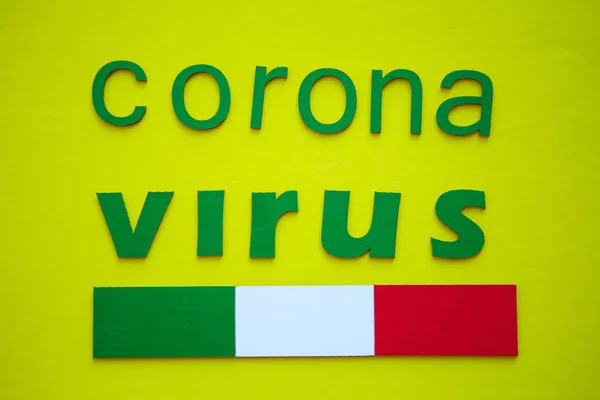 Bandera Italiana Y Palabra CORONAVIRUS hecha de letras de cartón verde, aislado sobre fondo amarillo. Organización Mundial de la Salud OMS presentó un nuevo nombre oficial para la enfermedad por Coronavirus llamado COVID-19 — Foto de Stock