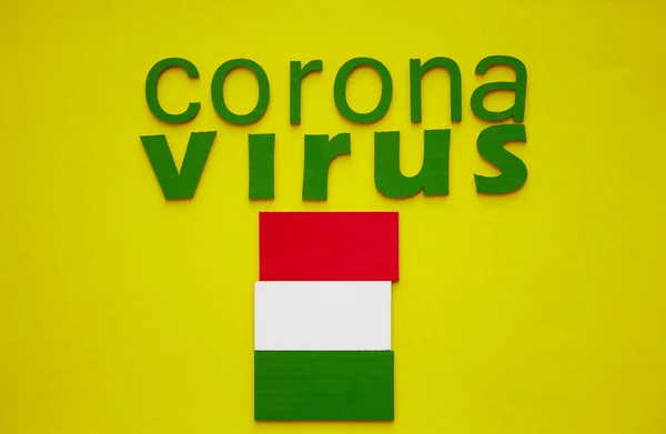 Hungarian Flag And Word CORONAVIRUS made of green cardboard letters, isolated on yellow background. World Health Organization WHO introduced new official name for Coronavirus disease named COVID-19. — Stock Photo, Image