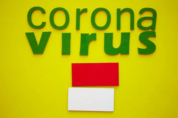 Flag of Monaco And Word CORONAVIRUS made of green cardboard letters, isolated on yellow background. World Health Organization WHO introduced new official name for Coronavirus disease named COVID-19 — Stock Photo, Image