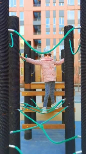 Chica juega en el parque de cuerdas. El concepto de descanso infantil en un entorno urbano. — Vídeo de stock