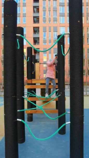 Chica juega en el parque de cuerdas. El concepto de descanso infantil en un entorno urbano. — Vídeo de stock