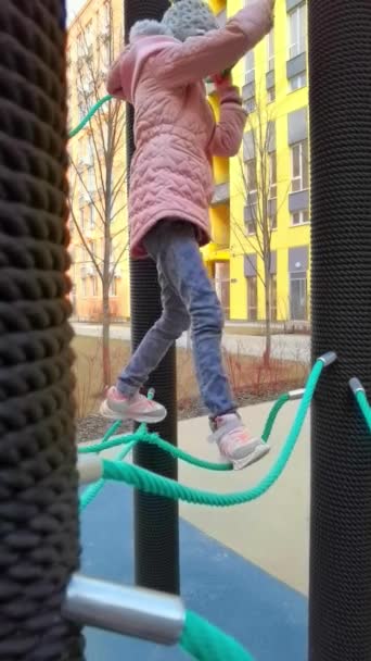 Chica juega en el parque de cuerdas. El concepto de descanso infantil en un entorno urbano. — Vídeos de Stock