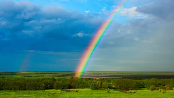O arco-íris sobre um campo após trovoada — Fotografia de Stock