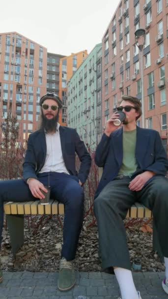 Dva mladí muži přátelé oblečeni ležérně tráví čas spolu ve městě, pití odnášející kávu další kolo. — Stock video