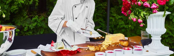 O garçom coloca no prato lanches de queijo. Aperitivo, catering em um casamento ou evento. — Fotografia de Stock