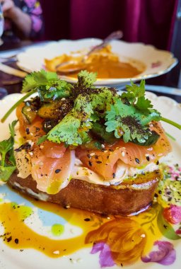 Açık yüzlü sandviç ya da kızarmış somon, avokado, kabak, fesleğen ve kıymalı soğan dilimli Fransız tartar ekmeği. Sayfalarda gösterilir.