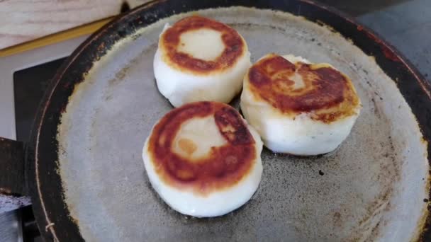 Close up shot of golden browned cottage cheese fritters fried rotating in a frying pan. Russian, Ukrainian, Belorussian cuisine. Preparing healthy tasty breakfast cheese cakes. — Stock Video