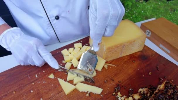 Las manos de las mujeres con un cuchillo de queso en rodajas en una tabla de cortar de cerca — Vídeos de Stock