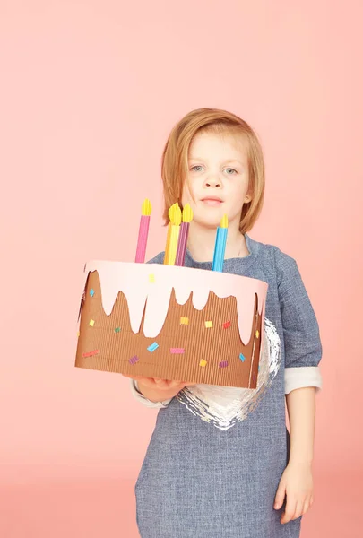 Ritratto di una bella ragazza eccitata che festeggia il compleanno e mostra la torta su sfondo rosa — Foto Stock