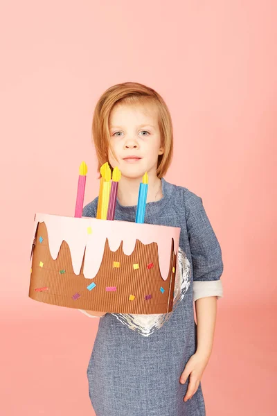 Portret podekscytowanej dziewczynki świętującej urodziny i pokazującej tort na różowym tle. — Zdjęcie stockowe