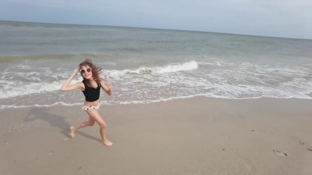 Kleines Mädchen spielt in den Ferien am Strand an der flachen Wasserlinie — Stockvideo