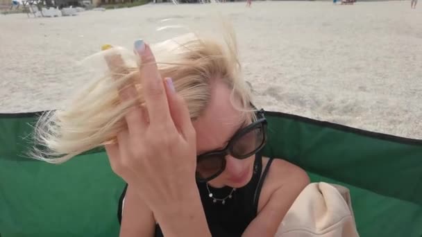 Ritratto al rallentatore volto di bella giovane donna con i capelli corti biondi guardando la fotocamera seduta sulla spiaggia di mare — Video Stock