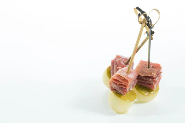 Amuse-gueule. Cuisine créative. Prosciutto à la poire sur fond blanc . — Photo