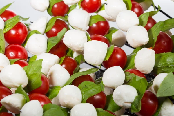 Aperitivo. mozzarella bebé con tomates cherry y hojas de albahaca . — Foto de Stock