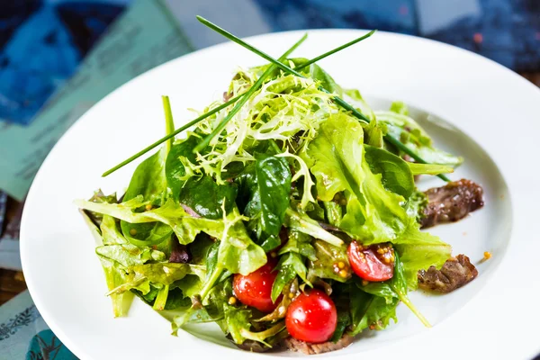 Свежий овощной салат с мясом и помидорами черри на белой тарелке . — стоковое фото