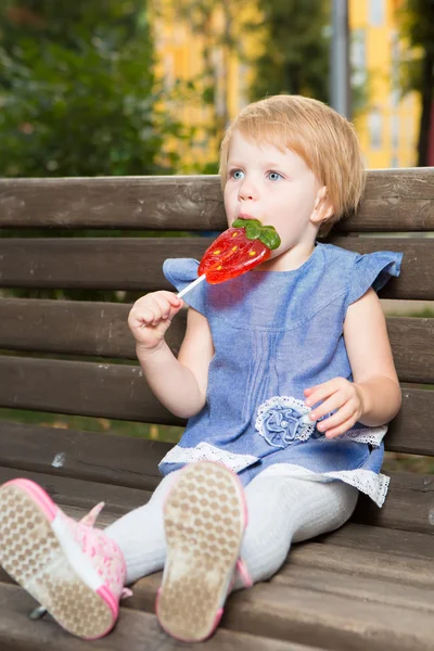 Bella bambina con in mano lecca-lecca a forma di fragola — Foto Stock