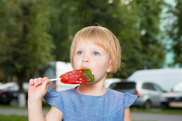 Beautiful little girl holding strawberry shaped lollipop — Stock Photo, Image