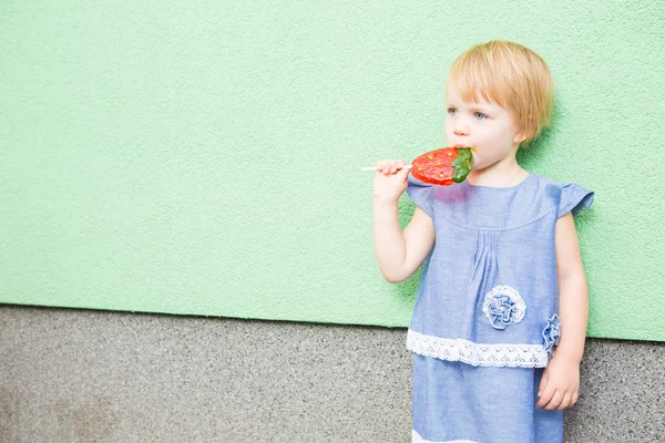 Beautiful little girl holding strawberry shaped lollipop — Stock Photo, Image