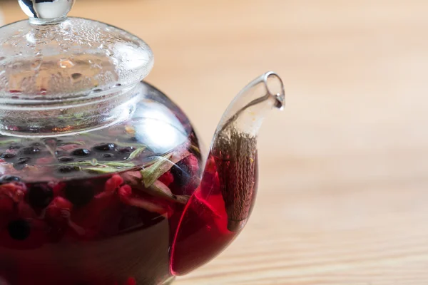 Hot tea with berries on wooden table — Stock Photo, Image