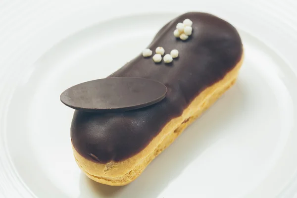 Jediného čokoládové Eclair na bílé desce — Stock fotografie