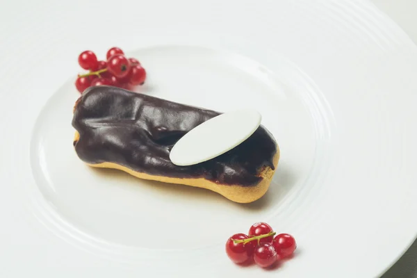 Ενιαία Eclair σοκολάτα στο άσπρο πιάτο — Φωτογραφία Αρχείου