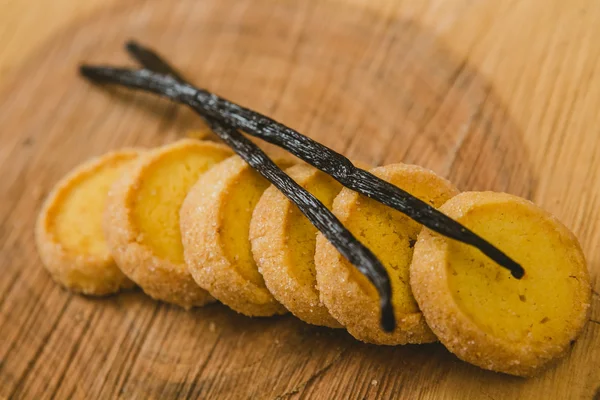 Biscotti di frolla al forno freschi con con bastoncini di vaniglia su un legno — Foto Stock