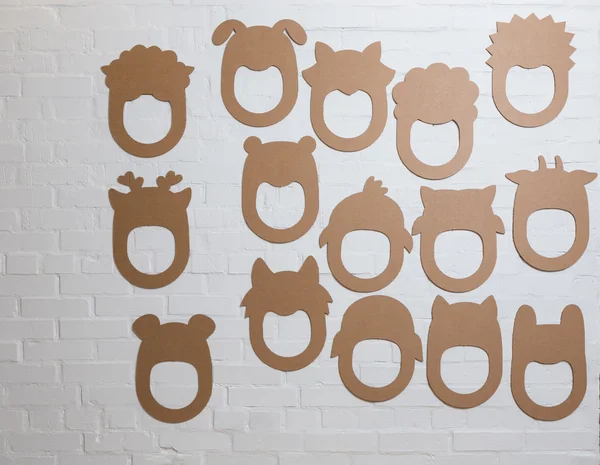 Set of cardboard masks on a white brick wall. — Stock Photo, Image