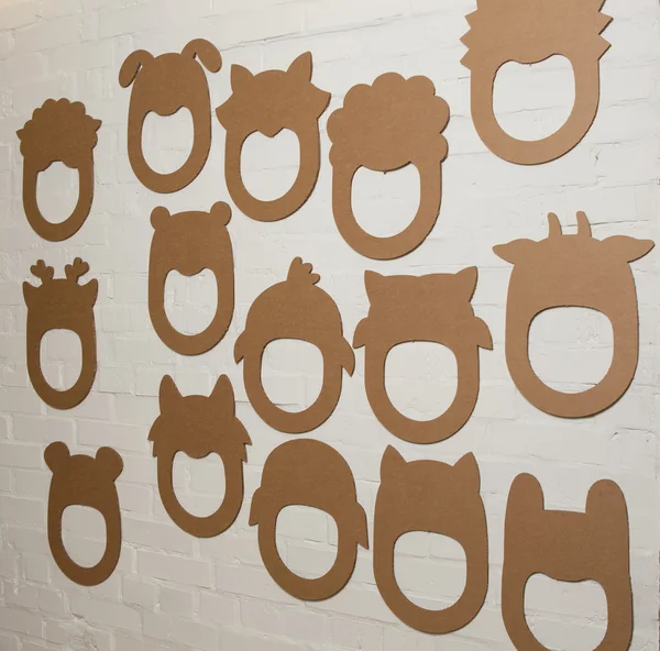 Set of cardboard masks on a white brick wall. — Stock Photo, Image