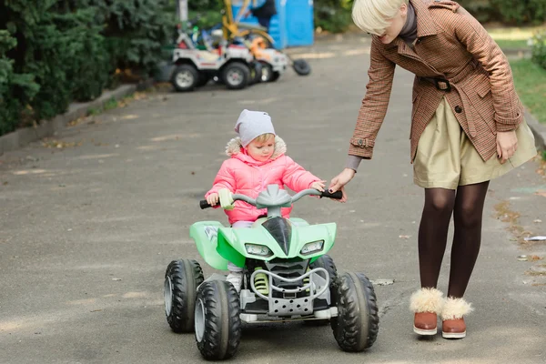 Meisje paardrijden speelgoedauto in park — Stockfoto