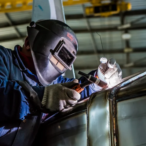 Soldagem de homem com reflexão de faíscas na viseira. Trabalho duro . — Fotografia de Stock