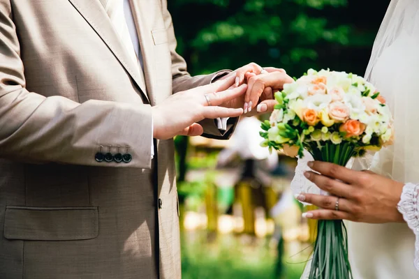 Mano mans mettendo una fede nuziale sul dito spose — Foto Stock