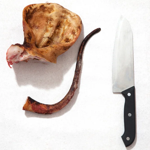 Orecchie di maiale con coltello e sfondo bianco sangue . — Foto Stock