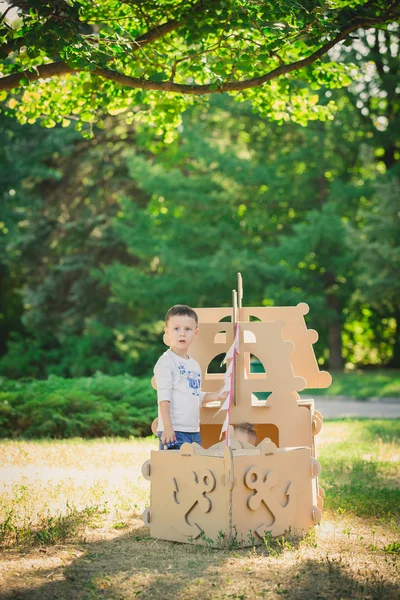 Pojke och flicka som leker i en kartong båt — Stockfoto