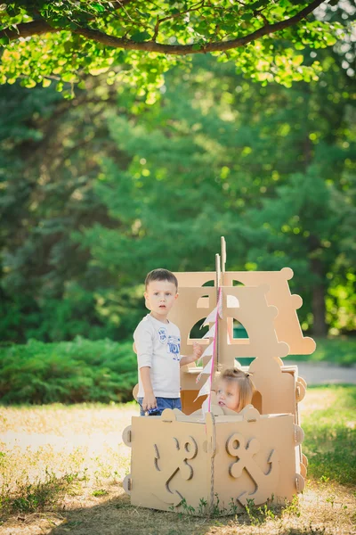 Boy and girl playing in a cardboard boat — Stock Photo, Image