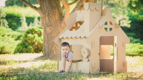 Boy playing in cardboard house — Stock Photo, Image