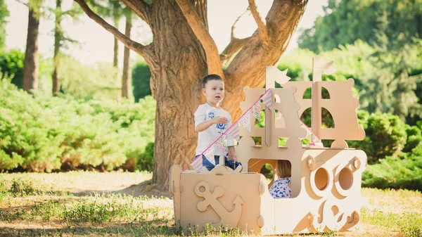 Junge und Mädchen spielen in einem Pappboot — Stockfoto