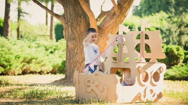 Boy and girl playing in a cardboard boat — Stock Photo, Image