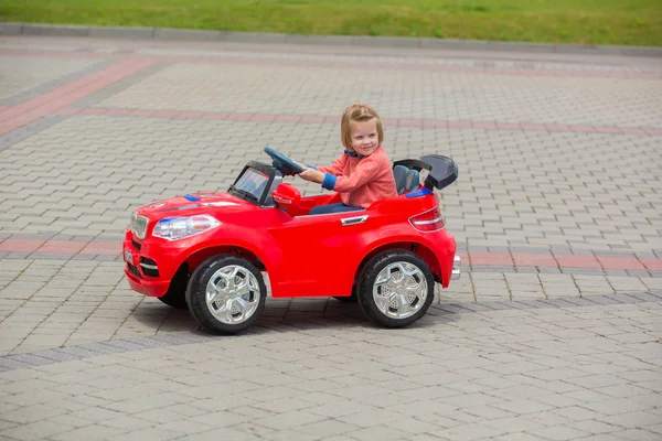 Bella bambina in sella giocattolo auto nel parco estivo — Foto Stock