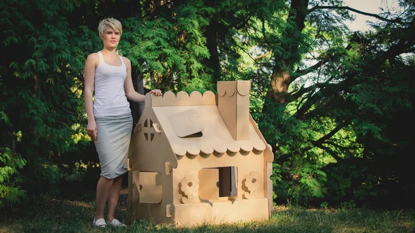 Attractive woman in the park with a cardboard house. — Stock Photo, Image