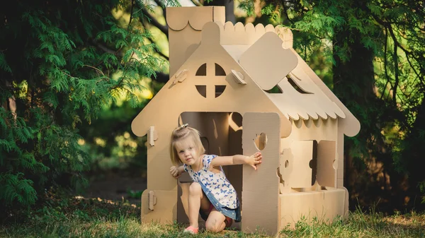 Girl playing cardboard house in a city park — Stock Photo, Image