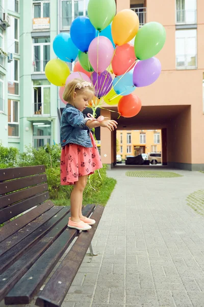 Glückliches kleines Mädchen im Freien mit Luftballons — Stockfoto