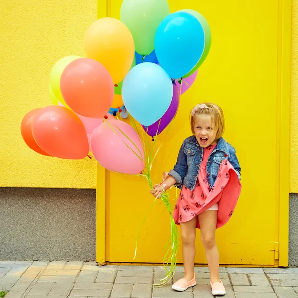 Счастливая маленькая девочка на улице с воздушными шариками — стоковое фото