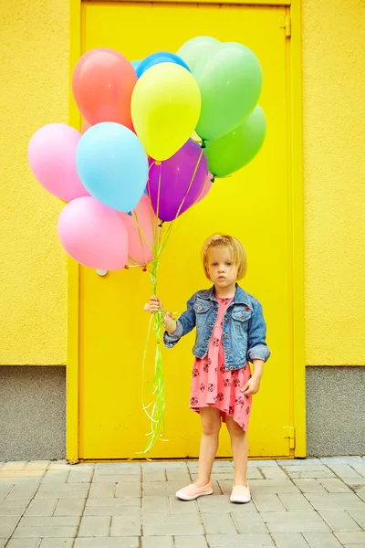 Glad liten flicka utomhus med ballonger — Stockfoto