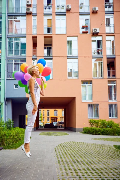 Happy young woman with colorful latex balloons — Stock Photo, Image