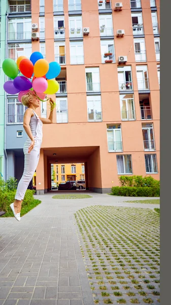 Happy young woman with colorful latex balloons — Stock Photo, Image