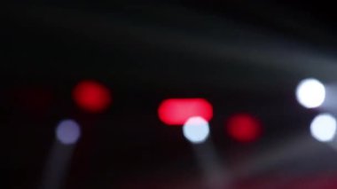 Karanlık bir sahnede canlı, bulanık ışıklar. Canlı olaylar, müzik, kutlama ve gece hayatı enerjisi için soyut bir arkaplan.