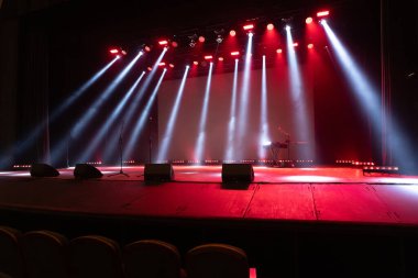 Boş bir sahnede sahne ışığı. Toplum önünde konuşma, liderlik, performans ve beklenti kavramı.